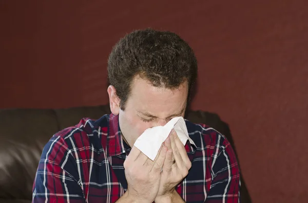 Kranker bläst Nase in ein Gewebe. Stockfoto