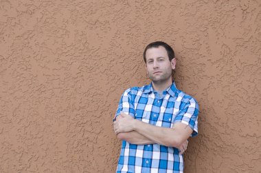 Adam kollarını ile bir duvara yaslanmış geçti.