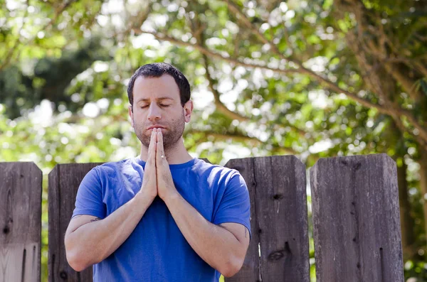 Adam dışında ahşap bir çit önünde dua.