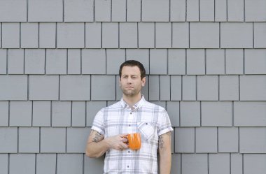 Bin yıllık adam nötr gri bir arka plan ile bir kahve kupa holding.