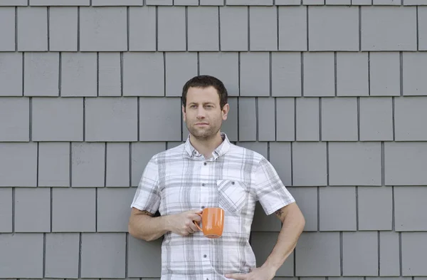 中立的な灰色の背景とコーヒーのマグカップを持って若い男. — ストック写真
