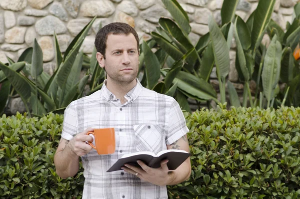 İyimser adam el kitabı ve kahve kupa ile bakan.