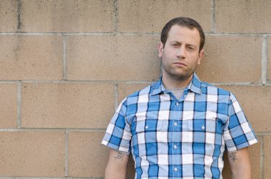 Sıkıntılı adam kirli bir beton duvara yaslanmış.