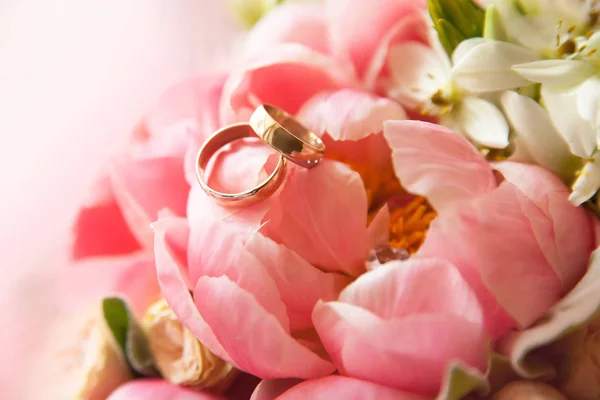 Dos anillos de boda de oro se encuentran en un ramo de flores, primer plano — Foto de Stock