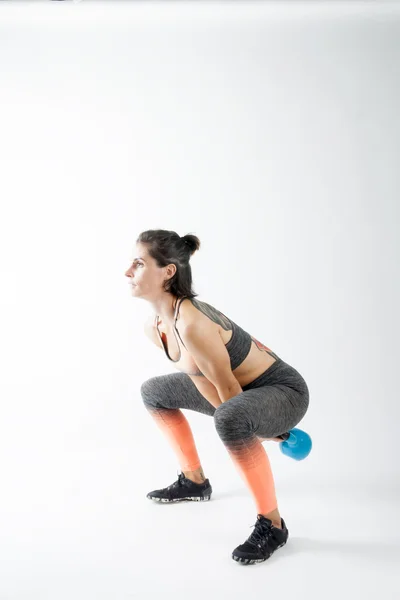 Beyaz arka plan üzerinde kettlebell ile egzersiz kız