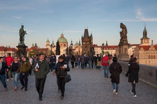 Prague, Tsjechië - 24 April 2017: toeristen op de Karelsbrug, met torens van de oude stad op de achtergrond — Stockfoto