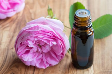 A bottle of rose essential oil with rose flowers in the background clipart