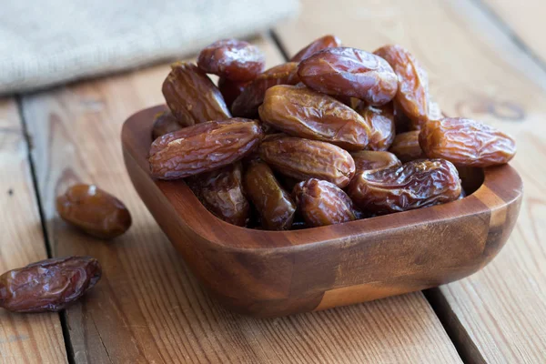 Dried dates in a bowl on a wooden table — Stock Photo, Image