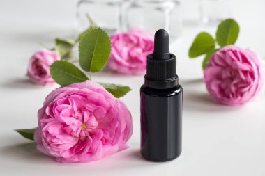 A bottle of rose essential oil with rose flowers clipart