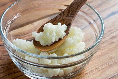 Kefir taneleri bir tahta kaşıkla bir cam kasede