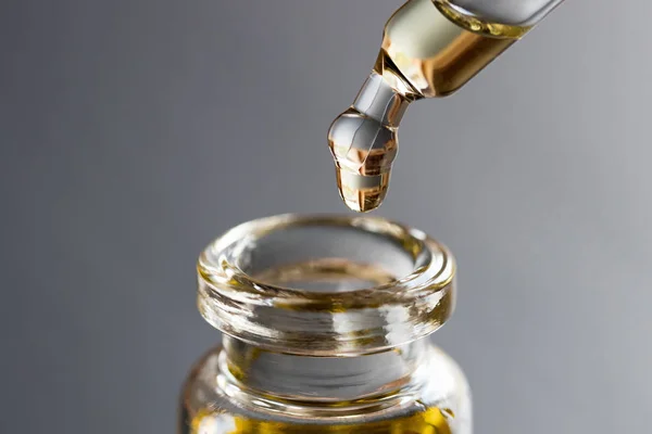 Una gota de aceite esencial está cayendo en una botella —  Fotos de Stock