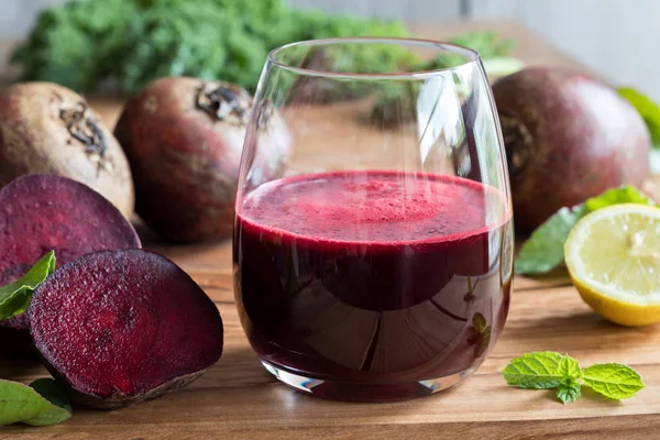 Jus de betterave rouge dans un verre sur un fond en bois — Photo