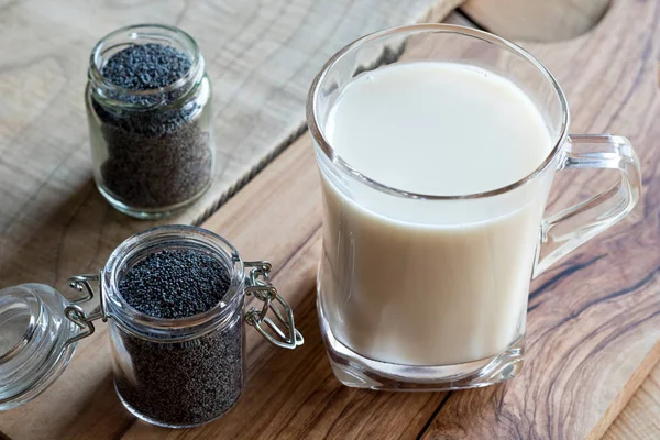 Um frasco de sementes de papoila com um copo de leite de semente de papoila — Fotografia de Stock