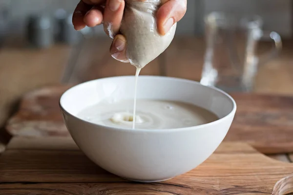Zubereitung von Nussmilch - Abseihen der Milch durch einen Milchbeutel — Stockfoto