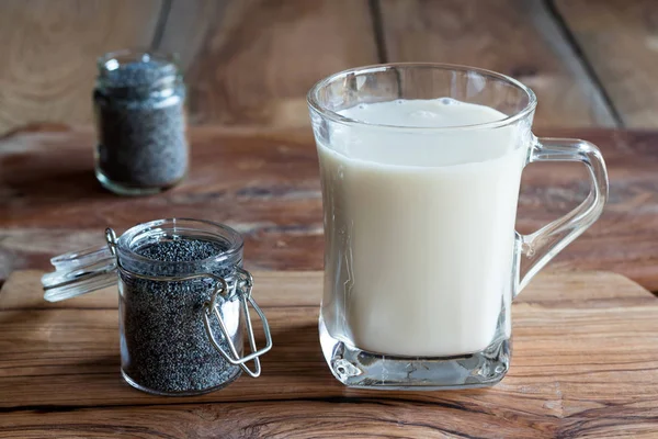 Um frasco de sementes de papoila com um copo de leite de semente de papoila — Fotografia de Stock