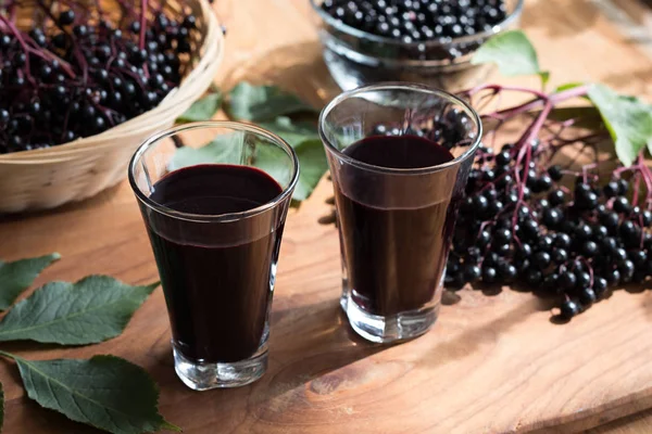 Dvě sklenice bezinkový sirup na dřevěný stůl — Stock fotografie