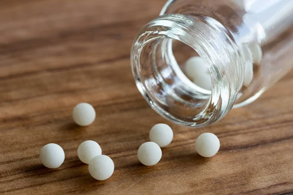 Homeopatik globüller ve ahşap arka plan üzerinde bir şişe