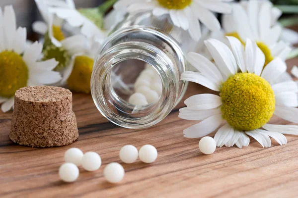 Una botella de pastillas homeopáticas con flores de manzanilla — Foto de Stock