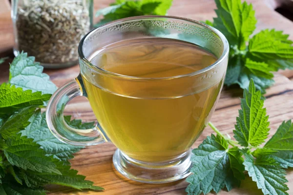 Een kopje brandnetel thee op een houten tafel — Stockfoto