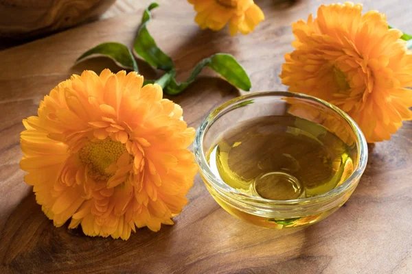 Aceite esencial de caléndula en un recipiente de vidrio con flores de caléndula — Foto de Stock
