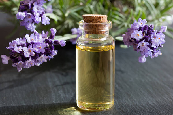 A transparent bottle of lavender essential oil on a dark backgro