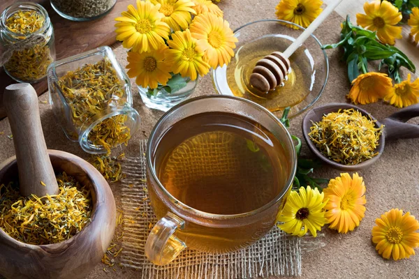 En kop calendula te med calendula i baggrunden - Stock-foto