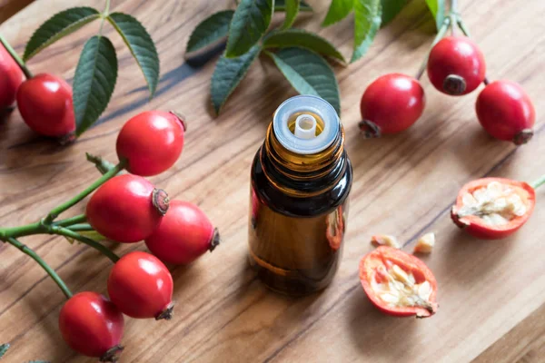 A bottle of rose hip seed oil on a wooden table — Stock Photo, Image