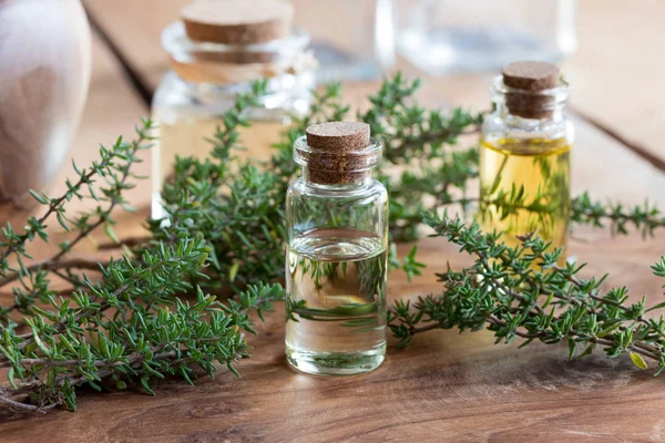 Een fles van essentiële tijmolie met takjes verse tijm — Stockfoto