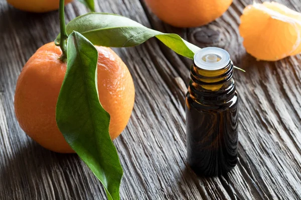 Una botella oscura de aceite esencial de mandarina sobre una mesa de madera — Foto de Stock