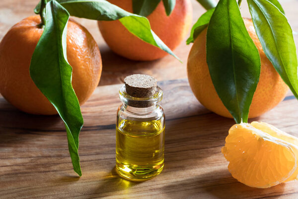 A bottle of tangerine essential oil on a wooden background