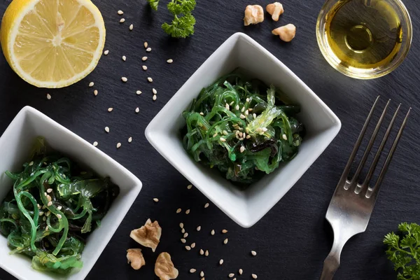 Fresh seaweed salad in two square bowls on a dark background — Stock Photo, Image