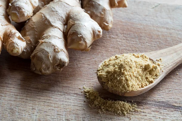 Backgr taze zencefil ile üzerinde bir tahta kaşık toz zencefil