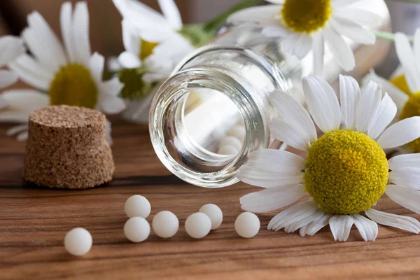 Una botella de glóbulos homeopáticos con flores de manzanilla — Foto de Stock