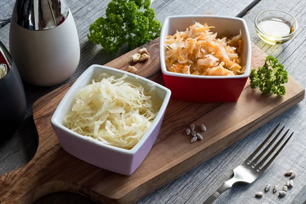 Fermented cabbage and carrots in two square bowls on a table