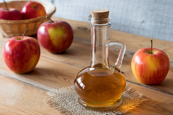Una botella de vinagre de manzana sobre una mesa de madera — Foto de Stock