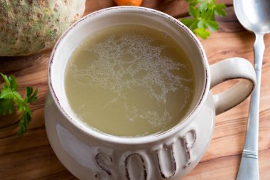 Ahşap bir masa üzerinde bir çorba kasesi tavuk yapılmış kemik suyu