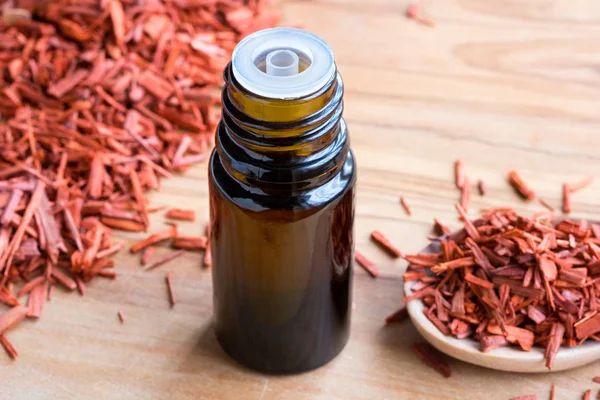 Een fles van sandelhout etherische olie met sandelhout op een houten — Stockfoto