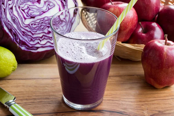 Пурпурный капустный сок в стакане, с капустой на заднем плане — стоковое фото