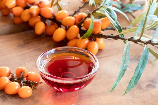 Sea buckthorn olie in een glazen kom met verse zee duindoorn branc — Stockfoto