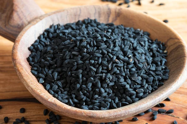 Семена черного тмина на деревянном фоне — стоковое фото
