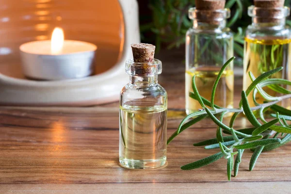 A bottle of rosemary essential oil with rosemary twigs and an ar — Stock Photo, Image