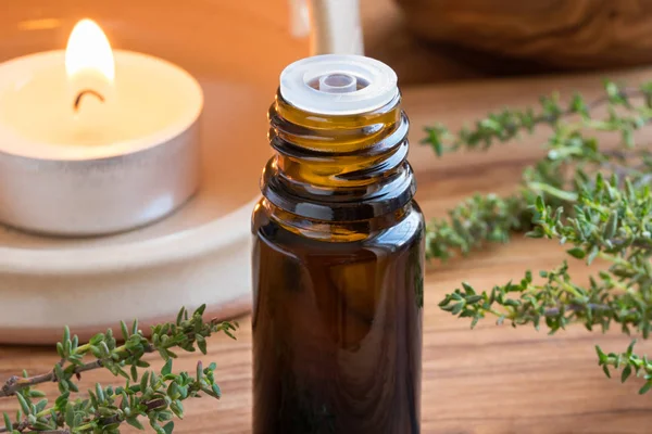 A dark bottle of thyme essential oil with fresh thyme twigs — Stock Photo, Image