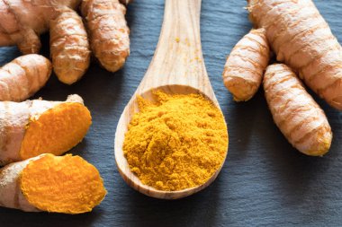 Bir kaşık ile taze zerdeçal kök üzerinde zerdeçal tozu