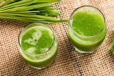 Two glasses of barley grass juice with fresh barley grass clipart
