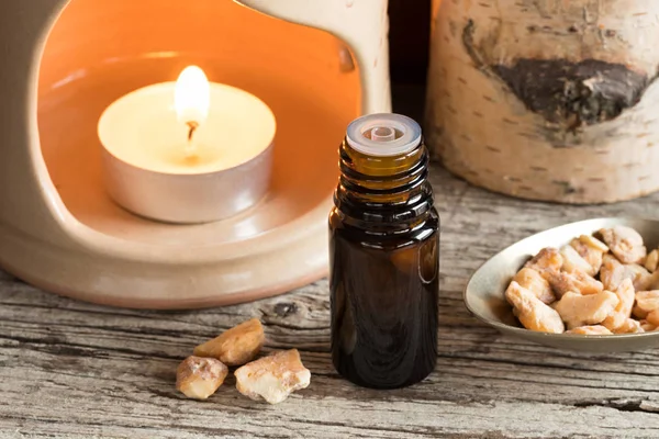 A bottle of styrax benzoin essential oil with benzoin resin and — Stock Photo, Image