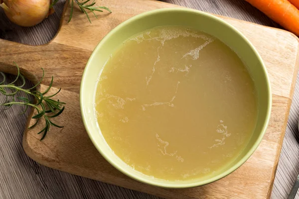 Caldo de galinha em uma tigela de sopa verde — Fotografia de Stock