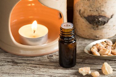 A bottle of styrax benzoin essential oil with an aroma lamp clipart