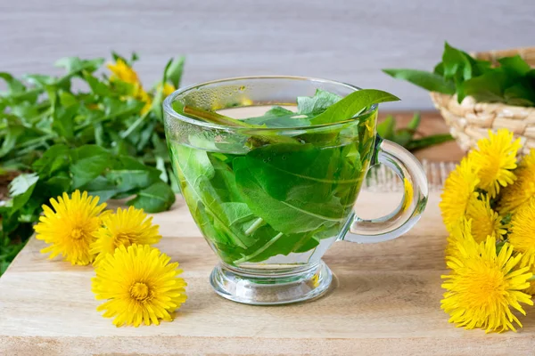 En kopp maskros te med färska blad och blommor — Stockfoto