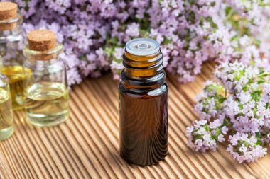 Taze çiçek açan kekik dallarıyla birlikte bir şişe gerekli yağ.