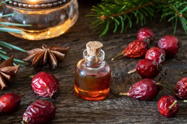 Kurumuş gül kalçalı bir şişe gül tohumu yağı.